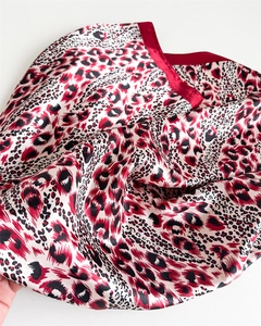 Close-up of leopard print satin silk scarf showing smooth texture and red border finish