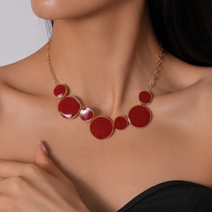 Gros plan d'un collier géométrique en émail rouge avec une chaîne dorée élégante
