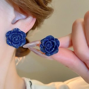 Gros plan d'élégantes boucles d'oreilles roses bleu foncé aux détails de pétales réalistes