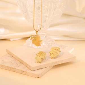 Golden irregular feather jewelry set with necklace and stud earrings on silk background