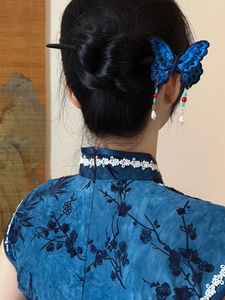 Détail d'une pince à cheveux papillon bleu brodé avec pompons de perles sur chignon