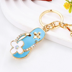 Close-up of light blue flip-flop keychain with gold edges and small sparkling crystals