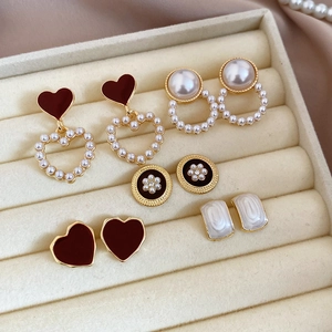 Close-up of vintage pearl and gold earring set displayed on beige velvet jewelry tray