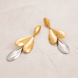 Macro detail of two-tone stainless steel leaf and teardrop earrings with gold plating