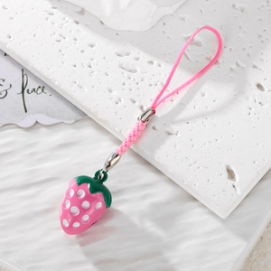 Detailed view of 3D pink strawberry charm with woven strap on a white stone surface