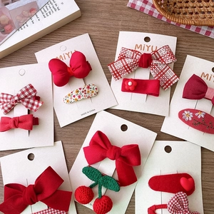 Détails des barrettes à nœud rouge festif et broderie cerise sur carte de support
