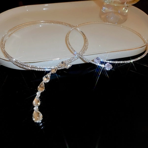 Close-up of sparkling zircon teardrop and heart necklaces on a white luxury tray