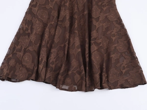 Détail du tissu en maille marron foncé avec broderie florale et ourlet sirène élégant