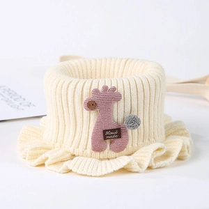 Close-up of cream knit baby cowl with pink giraffe patch and ruffle edge detail