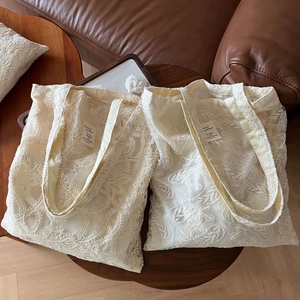 Detailed macro view of vintage beige lace floral embroidery on cotton canvas tote bags