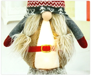 Close-up of glowing Christmas gnome with red snowflake hat and warm LED belly light