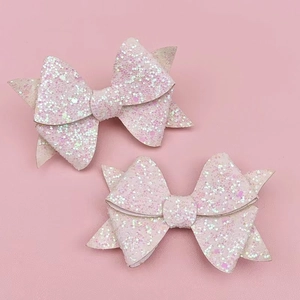 Detail of pink sequin bow hair clips with glitter finish on a soft pink background