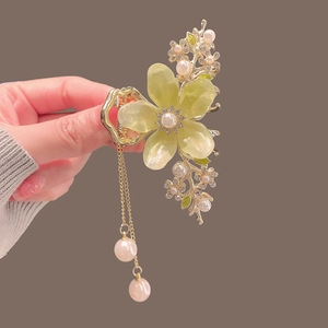Détail d'une pince à cheveux fleur verte élégante avec glands de perles et strass brillants