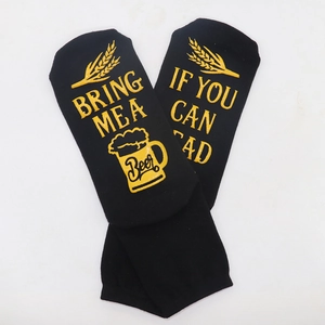 Macro view of black cotton socks with yellow non-slip lettering Bring Me A Beer on soles