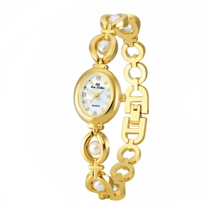 Detail of gold metal watch band featuring white pearls and diamond hour markers