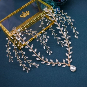 Detailed view of a golden bridal headband with leaf design and teardrop crystal accents