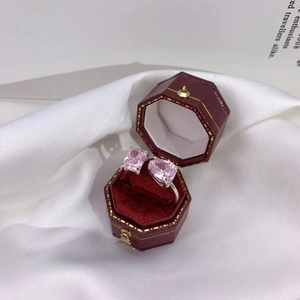 Macro shot of pink heart and emerald cut stones on silver ring in velvet box