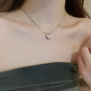 Close-up of minimalist silver crescent moon pendant necklace on a model's neck