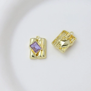 Detailed view of gold rectangle jewelry pendants with purple stone inlay and hollow back