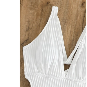 Close-up of white ribbed fabric detail on a sexy V-neck swimsuit on wood background