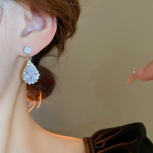 Close-up of elegant silver drop earrings with zircon crystals worn by a model