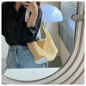 Detail of hollow woven straw shoulder bag with white leather straps and trim for summer