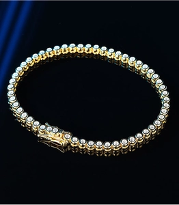 Macro shot of a gold tennis bracelet with round clear stones and lobster clasp closure