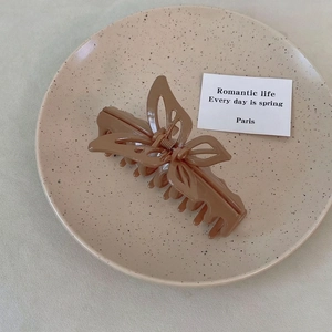 Detail of mocha brown butterfly hair claw clip with cutout wings on ceramic display tray