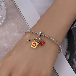 Macro shot of silver snake chain bracelet featuring breakfast toast and jam charms