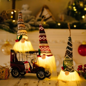 Three glowing Christmas gnomes with knitted hats and warm lights on a festive wooden table