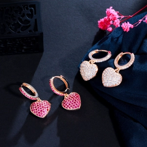 Gros plan sur les boucles d'oreilles cœur rose et cristal avec des zircons brillants
