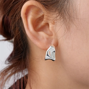 Close-up of minimalist liquid silver earrings with a mirror-finish flowing design