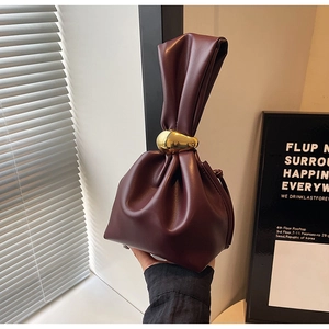 Close-up of wine red drawstring bucket bag with knotted handle and golden pebble buckle