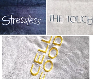 Detailed close-up of custom embroidered logos on soft coral fleece flannel blankets