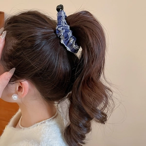 Détail d'un chouchou en tissu à carreaux bleu et blanc tenant une queue de cheval