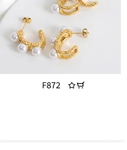 Gros plan de boucles d'oreilles C dorées avec texture martelée et perles sur soie blanche