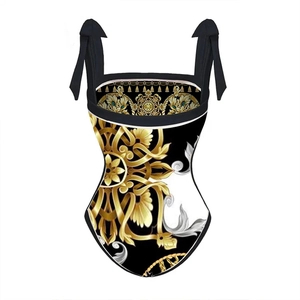 Détails des motifs baroques dorés et nœuds aux épaules sur le maillot une pièce noir