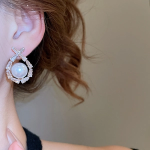 Close-up of pearl drop earrings with cubic zirconia inlay on a model's ear