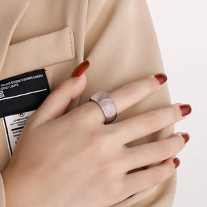 Close-up of wide silver titanium ring with translucent pink stone inlay on model hand