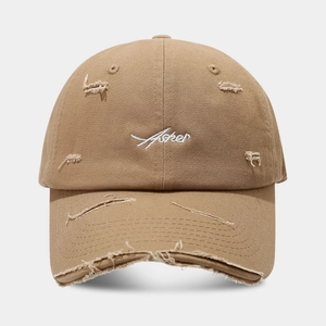Detailed view of khaki vintage baseball cap with distressed holes and white embroidery
