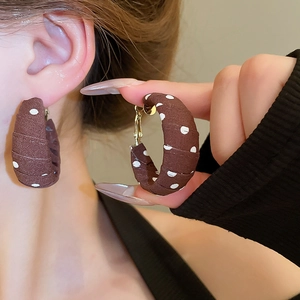 Detailed macro shot of vintage brown polka dot fabric wrapped C-shaped hoop earrings