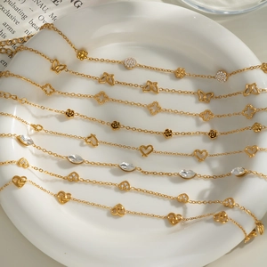 Macro view of assorted 18K gold plated chains with butterfly and crystal charms
