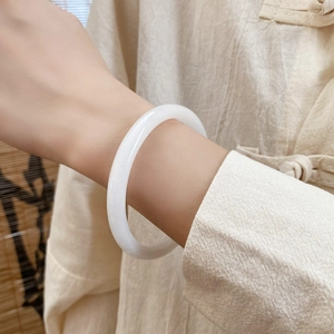 Gros plan sur un élégant bracelet jonc blanc style jade sur fond zen minimaliste