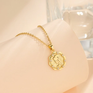 Gold coin necklace with princess relief and zircon stones on beige curved background