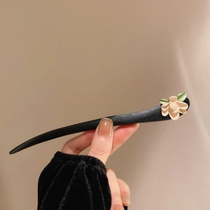 Vue détaillée de la fleur crème sculptée et des feuilles sur le pic à cheveux en bois