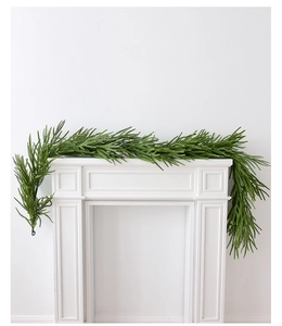 Close-up of Norfolk pine garland draped over a white fireplace for Christmas decor