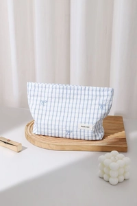 Dettaglio della trousse a quadretti blu con ricamo a fiocco ed etichetta in tessuto