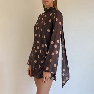 Detail von hochgeschlossenem Polka-Dot-Minikleid mit Bindeband und langen Ärmeln