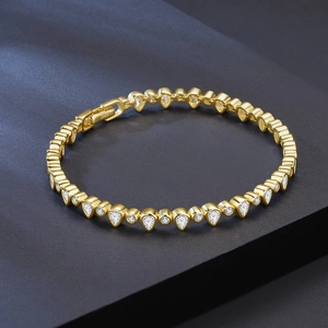 Close-up of gold plated S925 silver tennis bracelet with pear and round cut zircons