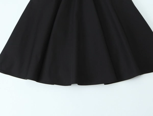 Detail shot of the pleated black dress hem showing neat stitching and smooth fabric texture